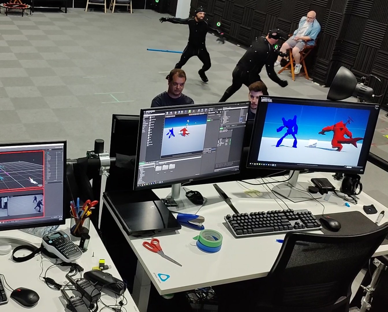Live body capture session: two performers driving blue and red digital characters rendered in Unreal Engine